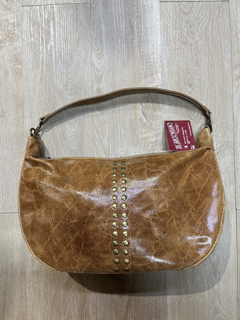 Bolso media luna de piel con tachuelas metálicas y asa corta, interior forrado con bolsillo con cremallera